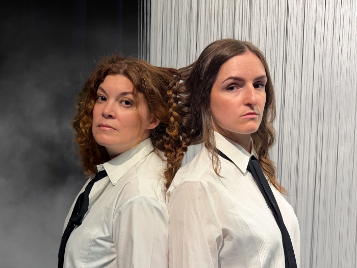 Auf dem Foto sieht man die Darstellerinnen von Brünhild und Kriemhild Rücken an Rücken stehen, ihre Haare sind miteinander verflochten