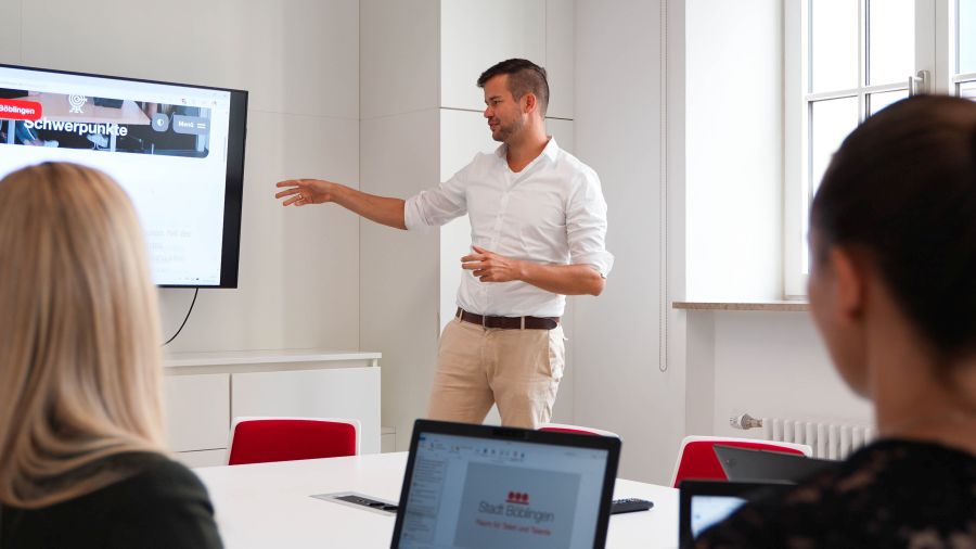 Mitarbeiter der Kämmerei, ein Mitarbeiter zeigt auf einen Bildschirm